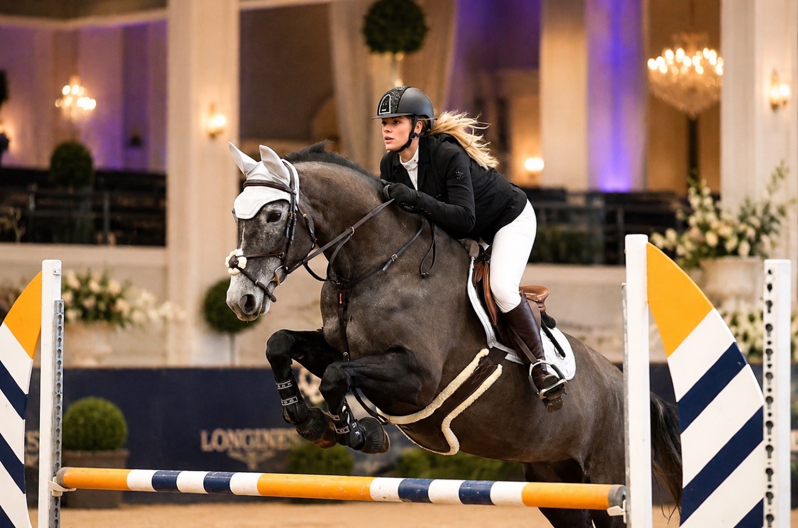 Harriet Smith riding over a fence in competition under Longines banners